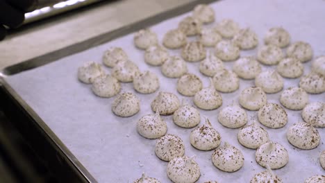 Baker's-Hand-In-Gloves-Taking-Meringue-Sprinkled-With-Coffee-On-Tray-With-Parchment-Paper