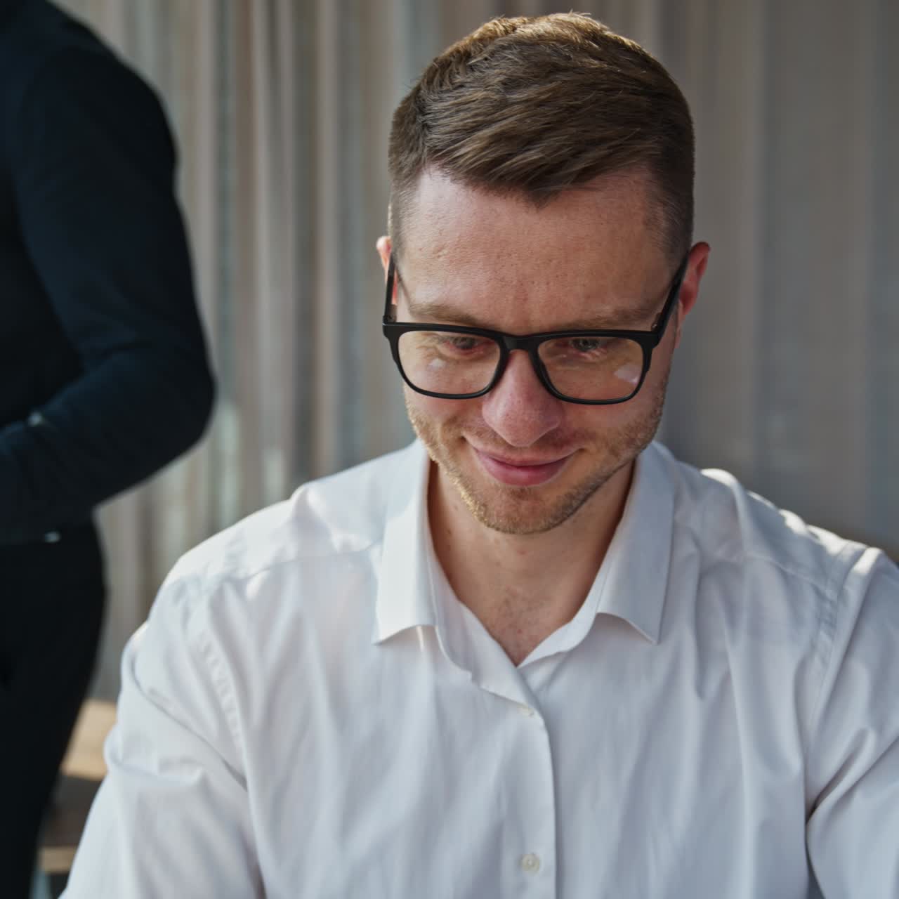 Partner commerciali che lavorano in ufficio. L'uomo con la maglietta nera è al telefono, mentre l'uomo con la camicia bianca lavora al laptop.