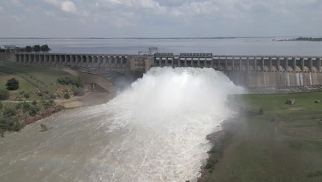 la niebla de la liberación de agua de la represa hidroeléctrica forma un arco iris sutil sobre el río