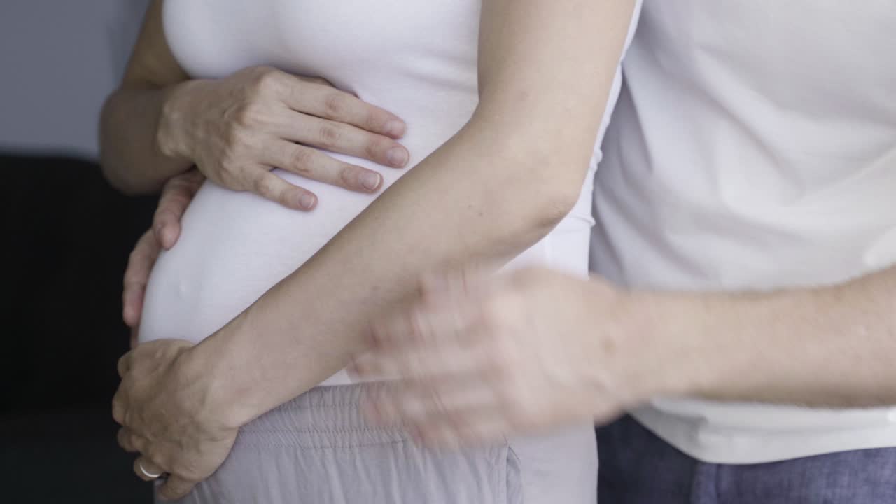 передний вид веселой пары, разговаривающей и протирающей живот