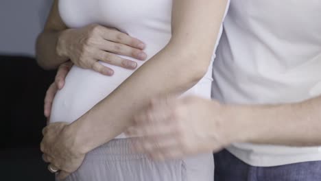 vista frontal de una pareja alegre hablando y frotando el vientre