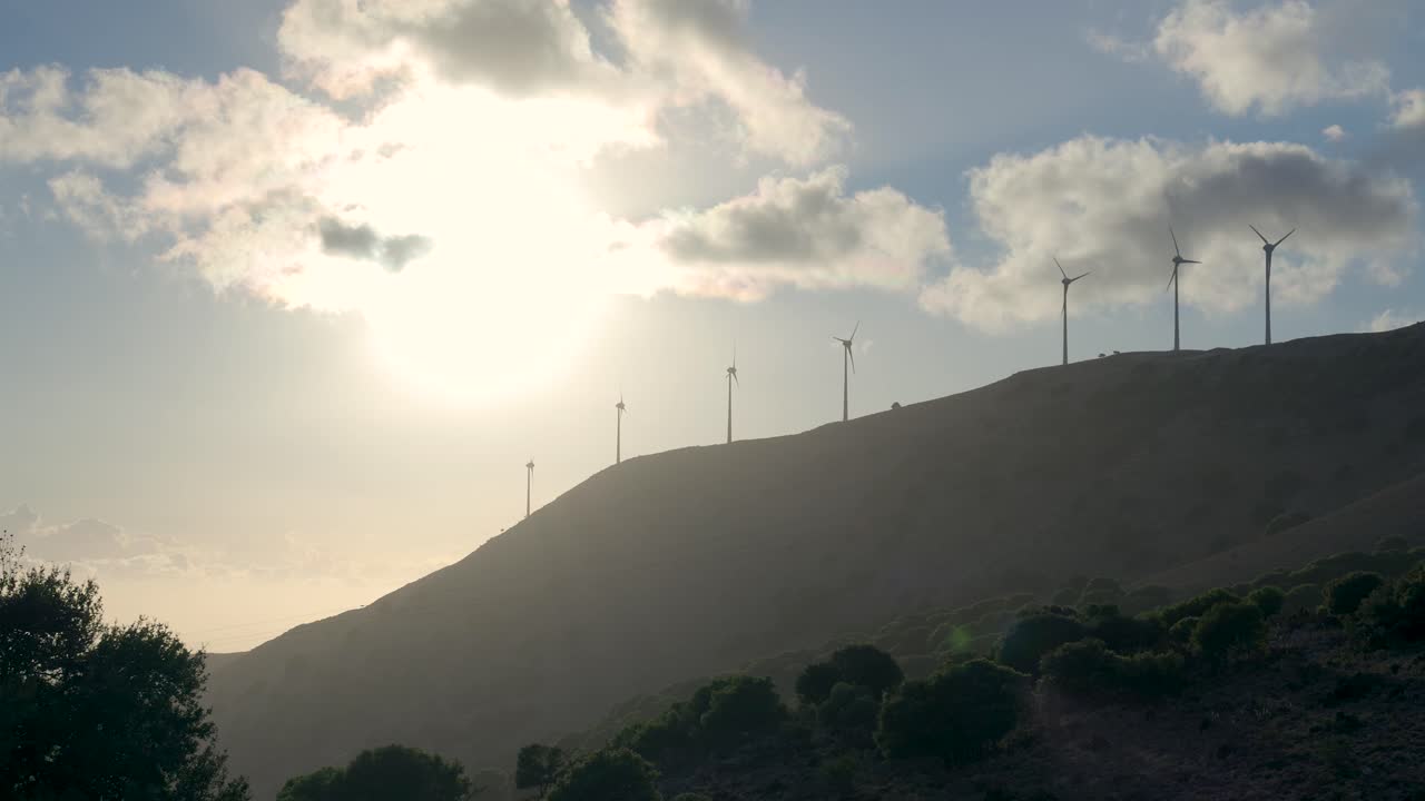 해가 지는 동안 언덕 꼭대기에 있는 풍력 발전소