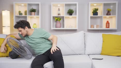 Man-overwhelmed-by-hot-air-cools-down-with-fan.