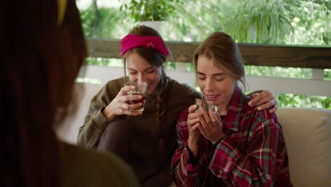 comunicación de chicas hermosas en un gazebo en la naturaleza. una chica con una camisa roja una chica con una camiseta verde beber té y charlar con su amiga