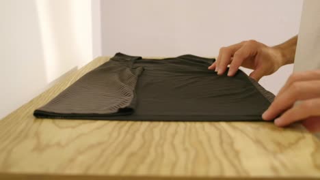 male hands folding clothes on wooden surface