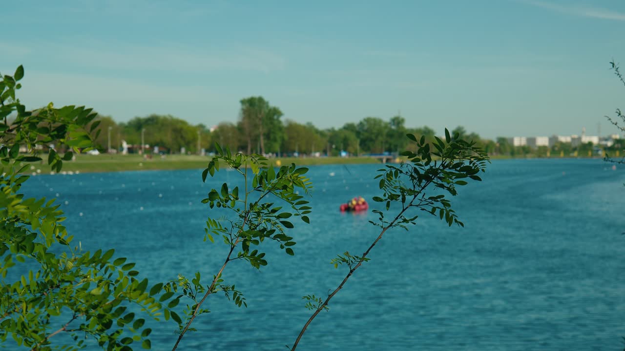 Serene waters of Jarun Lake framed by verdant foliage, with distant paddlers in Zagreb, Croatia