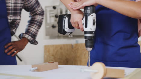 close up of trainees in workshop learning how to use power tools to assemble bicycle