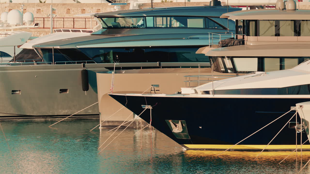 Diversi yacht di lusso moderni ormeggiati in un porticciolo turistico, con il caldo sole che si riflette sull'acqua calma