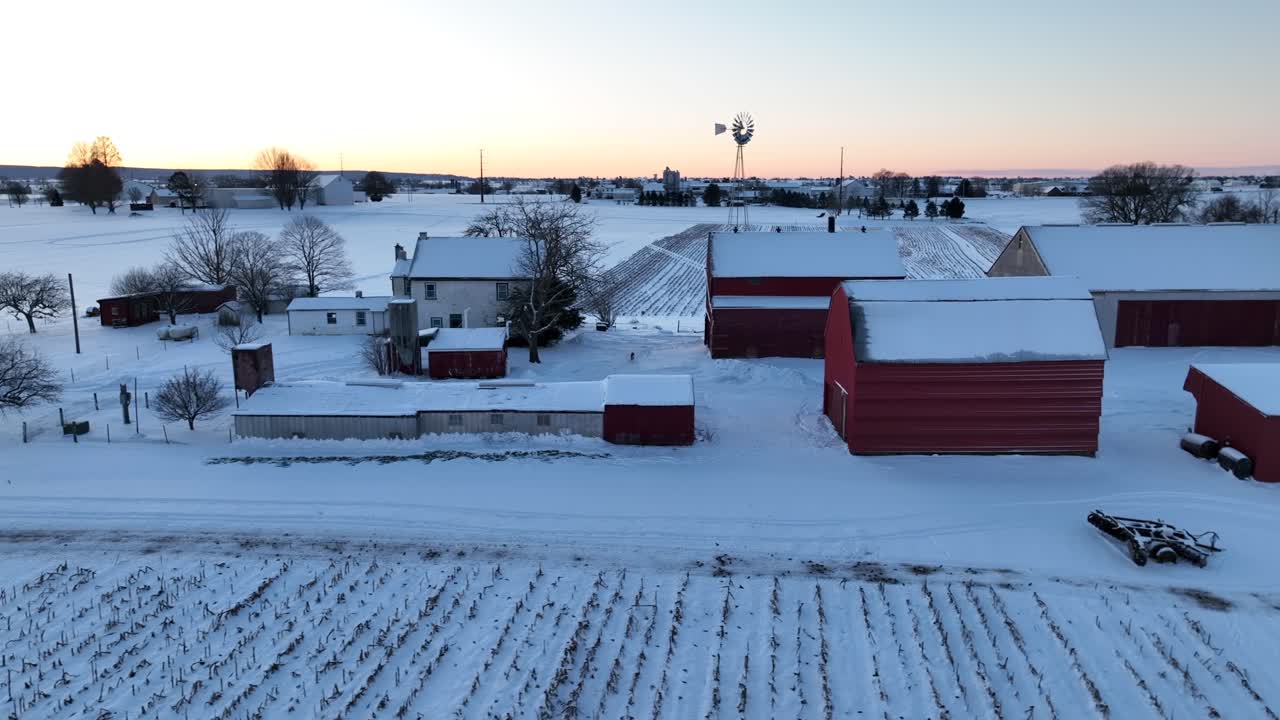 Amerikansk gård dækket af sne under vintersolopgang
