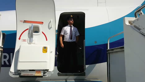 steward se encuentra en el umbral de la puerta del avión