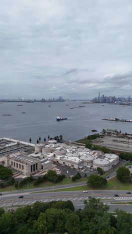 a drone push-in shot over senator street in brooklyn, gradually revealing the expansive view of upper bay, with the surrounding urban landscape and waterfront in view.