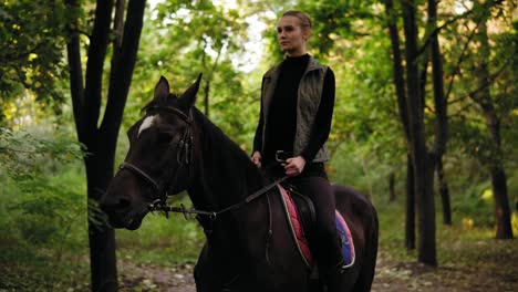 mujer atractiva montando un hermoso caballo marrón en el parque durante un día soleado. hermosa jinete mujer sentada en la silla de montar en semental y