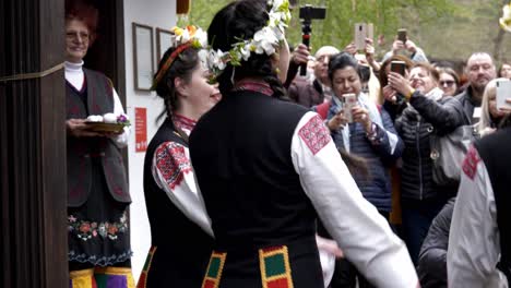 pretty, bulgarian girls in colourful traditional dress perform easter time ritual dance in front of crowds slow mo.