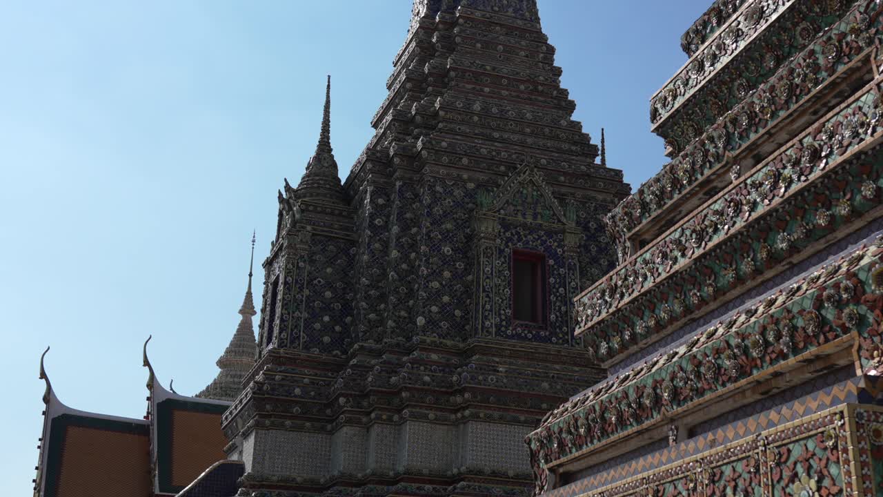 Detail of the mosaic-covered chedis and temple spires at Wat Pho, Bangkok, Thailand. Intricate traditional Thai Buddhist architecture and glazed ceramic tiles