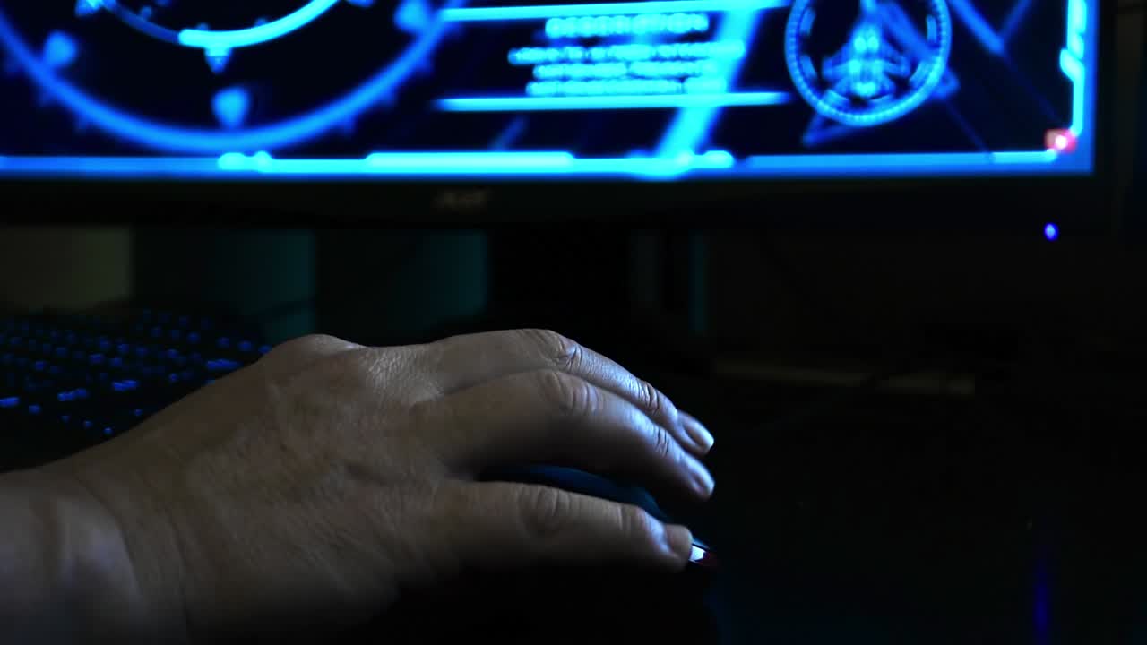 Close up of a hacker's hand using a computer mouse, hi-tech screen in the background