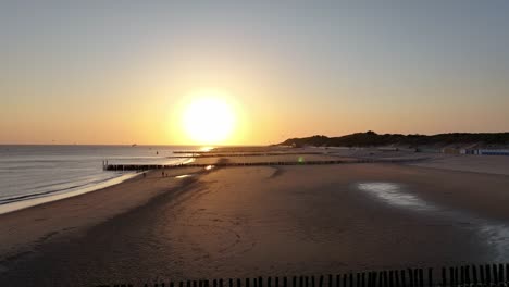 Hermosa-Puesta-De-Sol-En-Una-Playa-De-Arena-Con-Mar-En-Calma-Y-Muelle