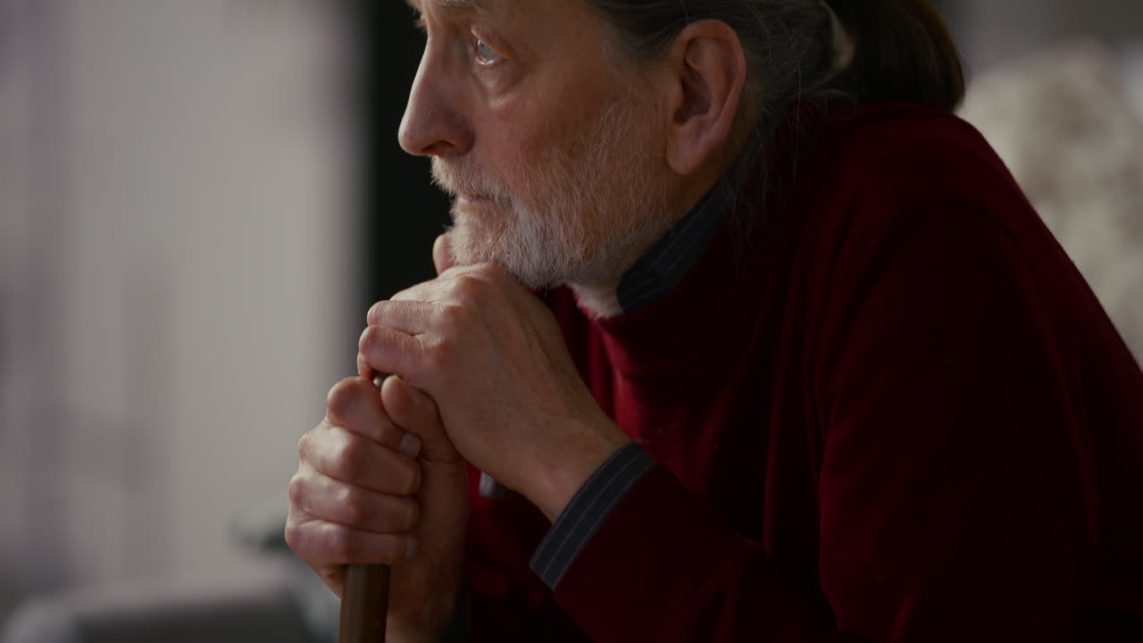 Elderly Man Sitting Thoughtfully with a Walking Stick