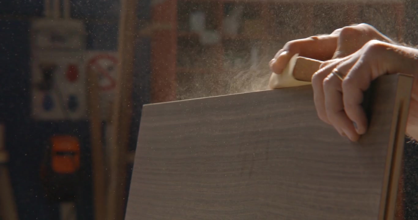 Primo piano al rallentatore di un falegname che leviga un'asse di legno.
