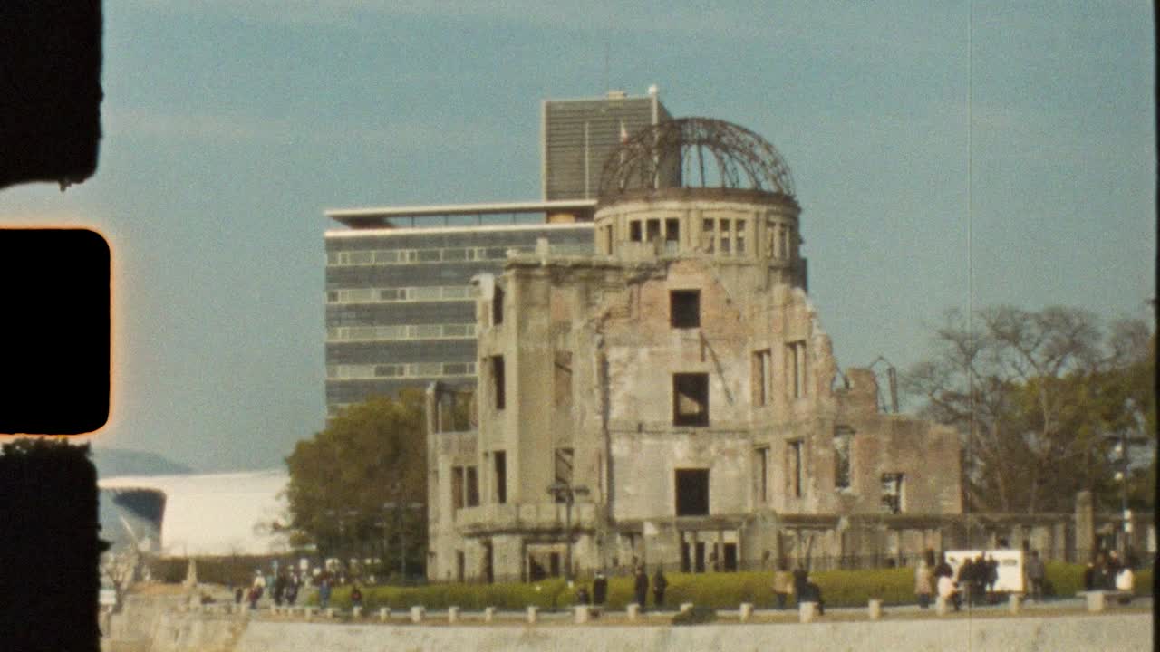 Filme vintage Super 8 mm de turistas perto do edifício marco Cúpula Genbaku ao longo da orla ribeirinha do Rio Motoyasu no Parque Memorial da Paz na cidade de Hiroshima, Japão. Turismo e história na Ásia.