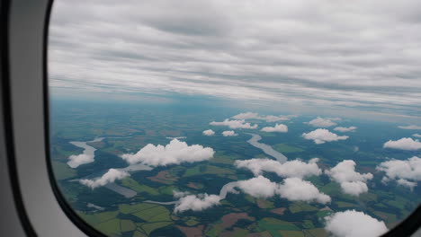 aerial view of rivers and fields through an airplane window on a cloudy day
