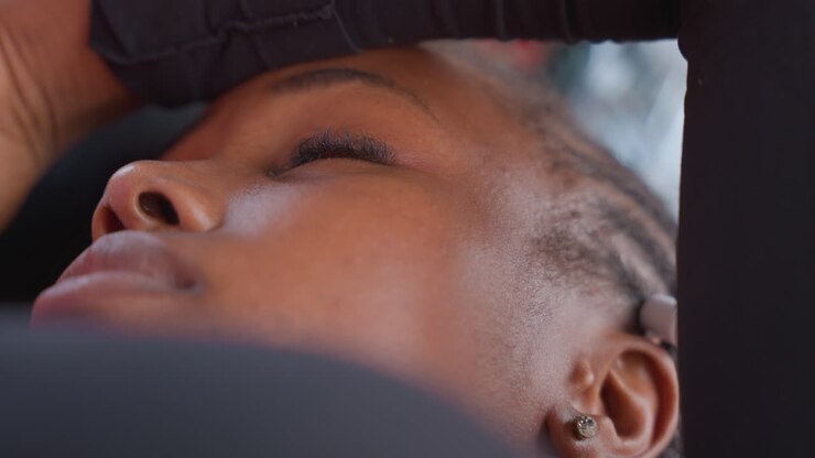 Athlete takes break. Black athlete pauses after exercise session. Closeup of athlete relaxing following strenuous workout. Focused shot of sports person resting with sweaty skin and braided hair