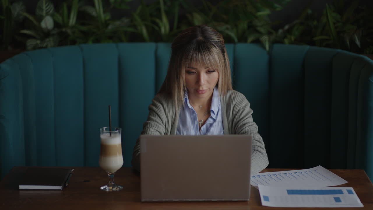 una estudiante asiática escribe una conferencia en línea en el campus con un bolígrafo. sentada en la biblioteca una estudiante coreana escucha una conferencia