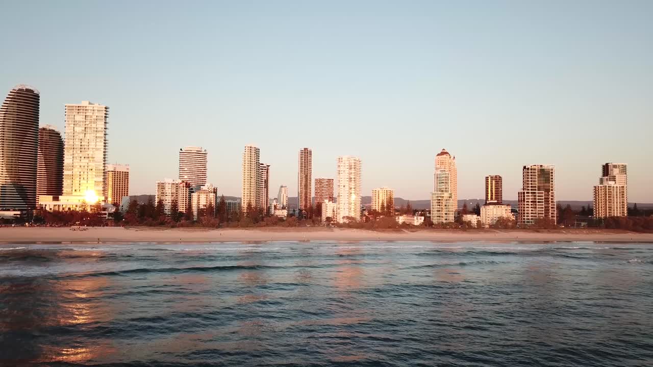 해가 뜨는 동안 해변에 파도가 치는 브로드비치 도시 상공의 드론 공중