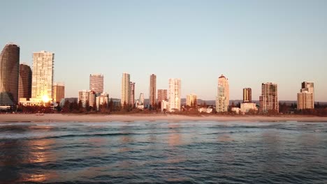 drone aerial over broadbeach city with waves on the beach during sunrise