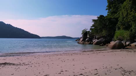 Tropical-paradise-sunset-evening,-sandy-beach-alongside-lush-forest-clear-blue-water