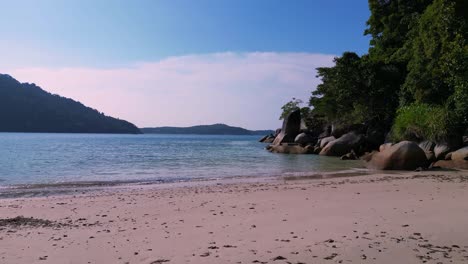 un paraíso tropical al atardecer, una playa de arena junto a un bosque exuberante y aguas azules claras