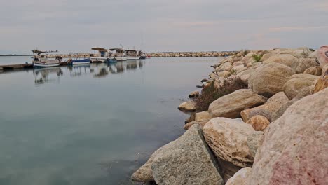 greek boats moored in peaceful calm rock boulder harbour at twilight