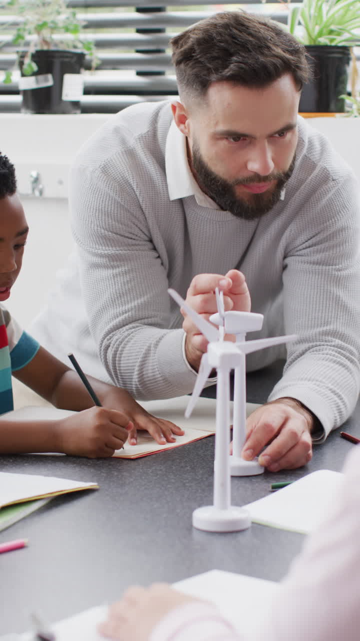 Vertical video of happy diverse male teacher and schoolchildren in school classroom