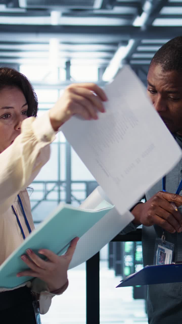Vertical video Team of IT professionals looking over data center checkup checklist paperwork