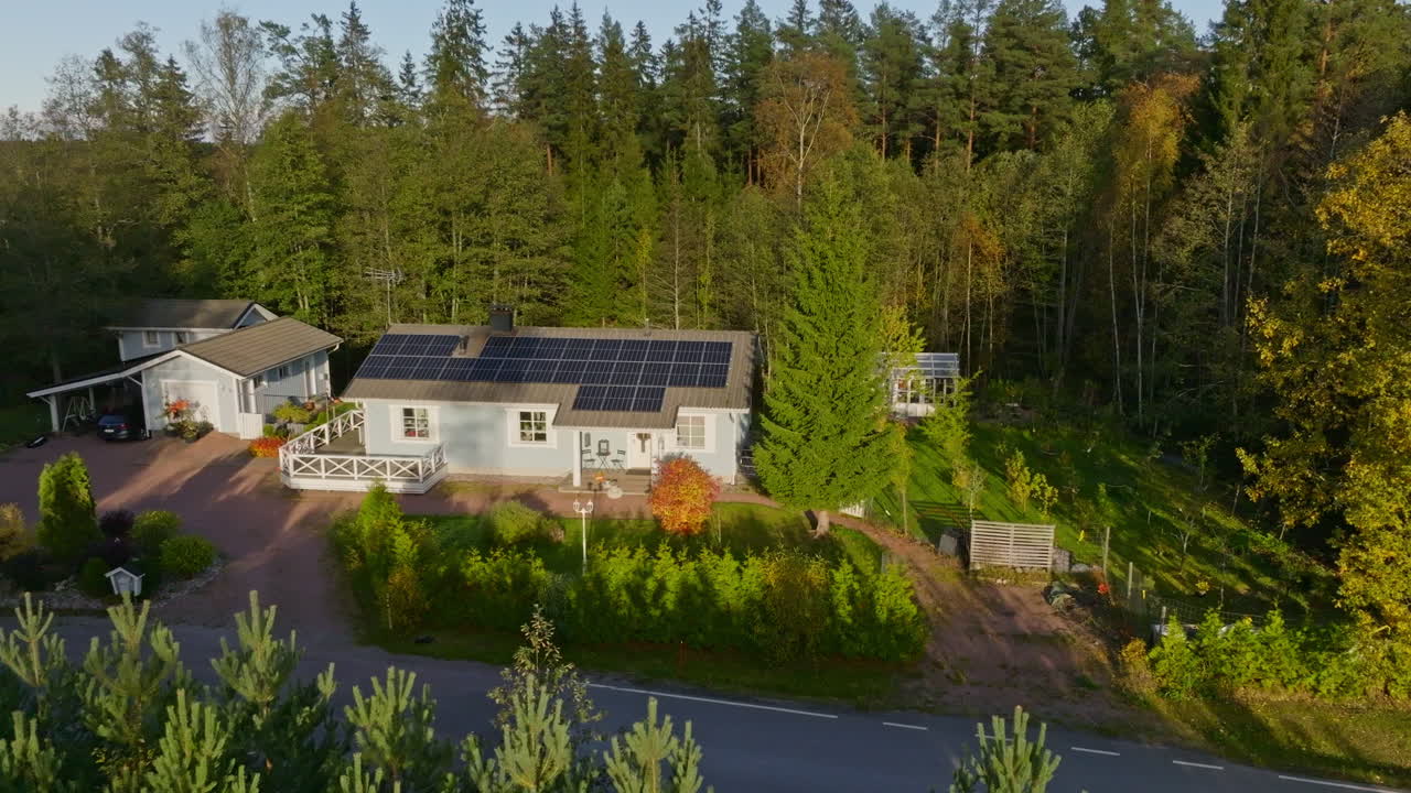 Aerial view orbiting a solar powered house in middle of forest, fall golden hour