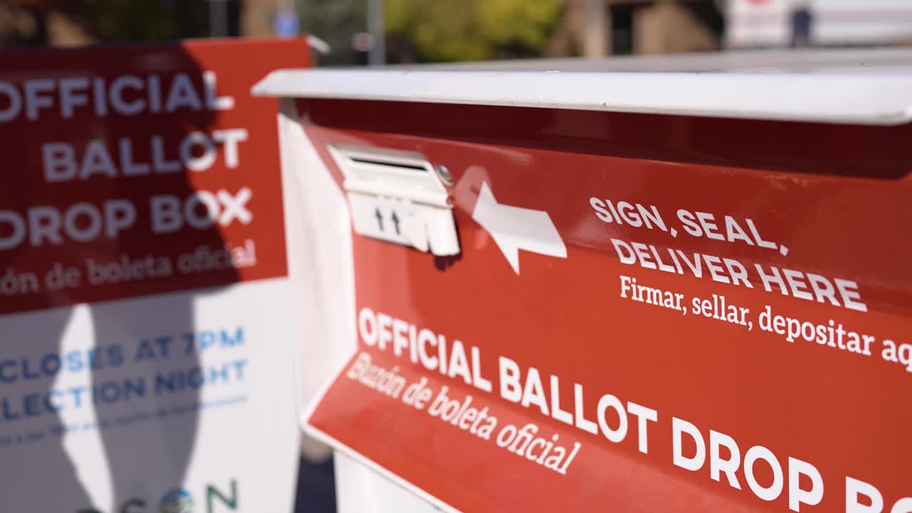 Young Man Places Mail-In Ballot Envelope in Official Voting Drop Box Beside Drop Ballot Here Sign