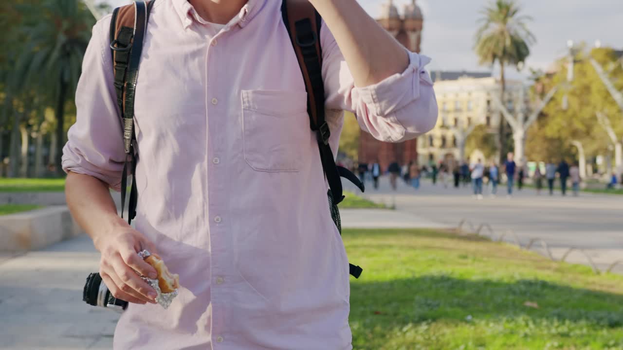 A man with a backpack and camera walking in a park