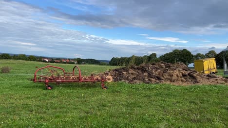 plano general estático de algunos equipos agrícolas y una pequeña colina de estiércol cerca de la ciudad de kaufbeuren, alemania