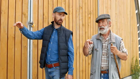 viejo padre e hijo granjeros caminando y hablando fuera del establo