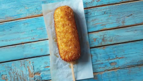 closeup of a crispy fried corn dog on a stick