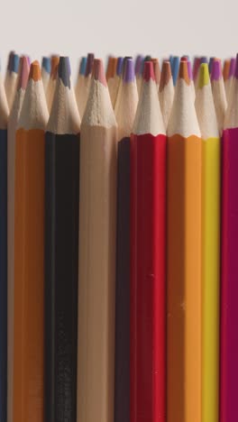 fotografía de estudio de video vertical de lápices multicolores giratorios contra un fondo blanco