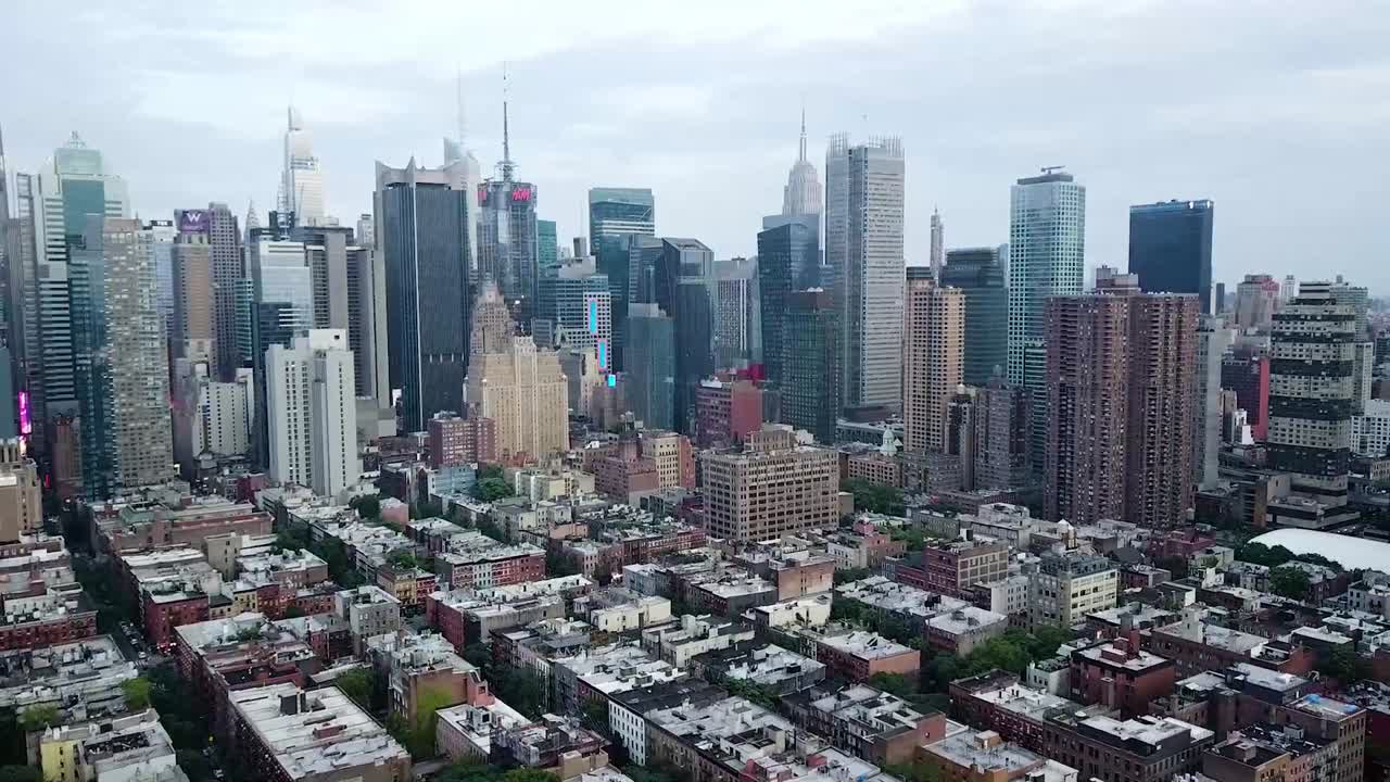 American neighborhood of Manhattan in New York City and Skyline in background. Aerial backwards wide shot. Housing area with luxury homes in USA. Empire State Building and Times Square