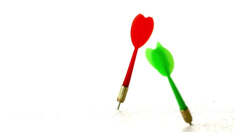 Red-and-green-darts-piercing-white-surface-