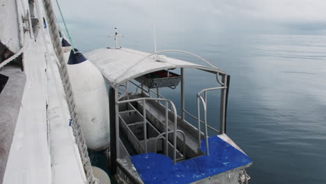 a small scuba dive boat, secured by a line to a larger vessel, bobs gently in the turquoise water