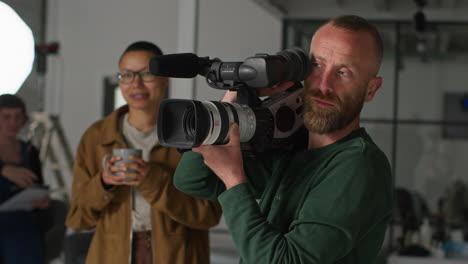 female film director talking with male camera operator shooting movie or video in studio 6