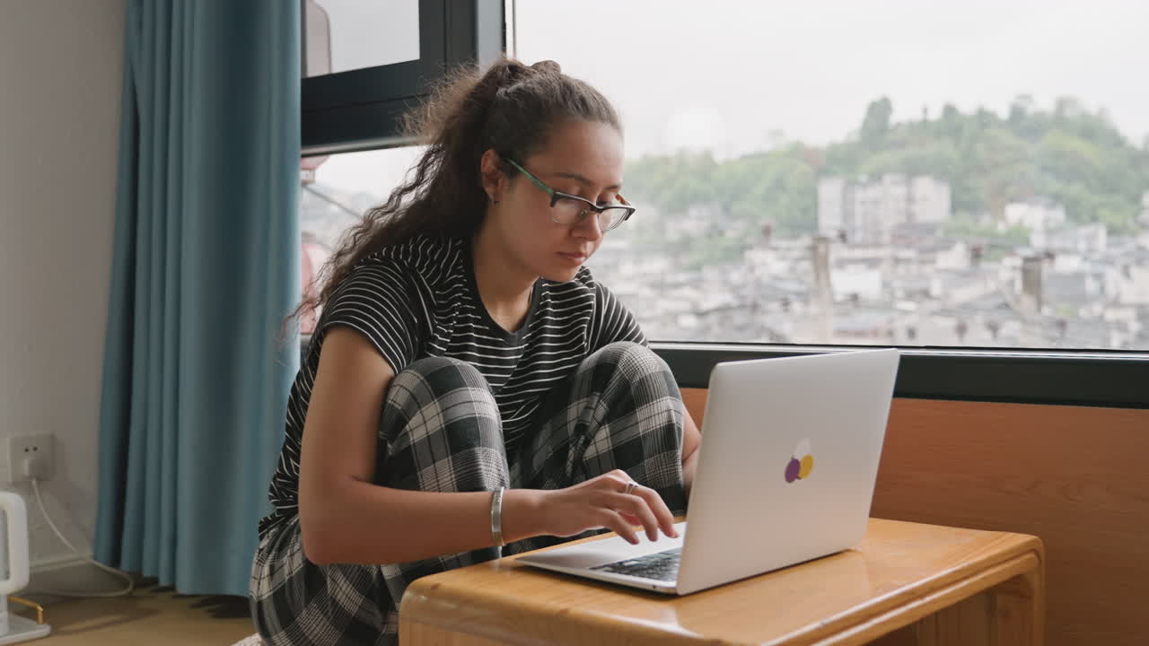 Journey arrangement view. Person arranging travel itinerary while observing urban landscape outside window. User organizing travel route using maps from balcony overlooking vibrant cityscape