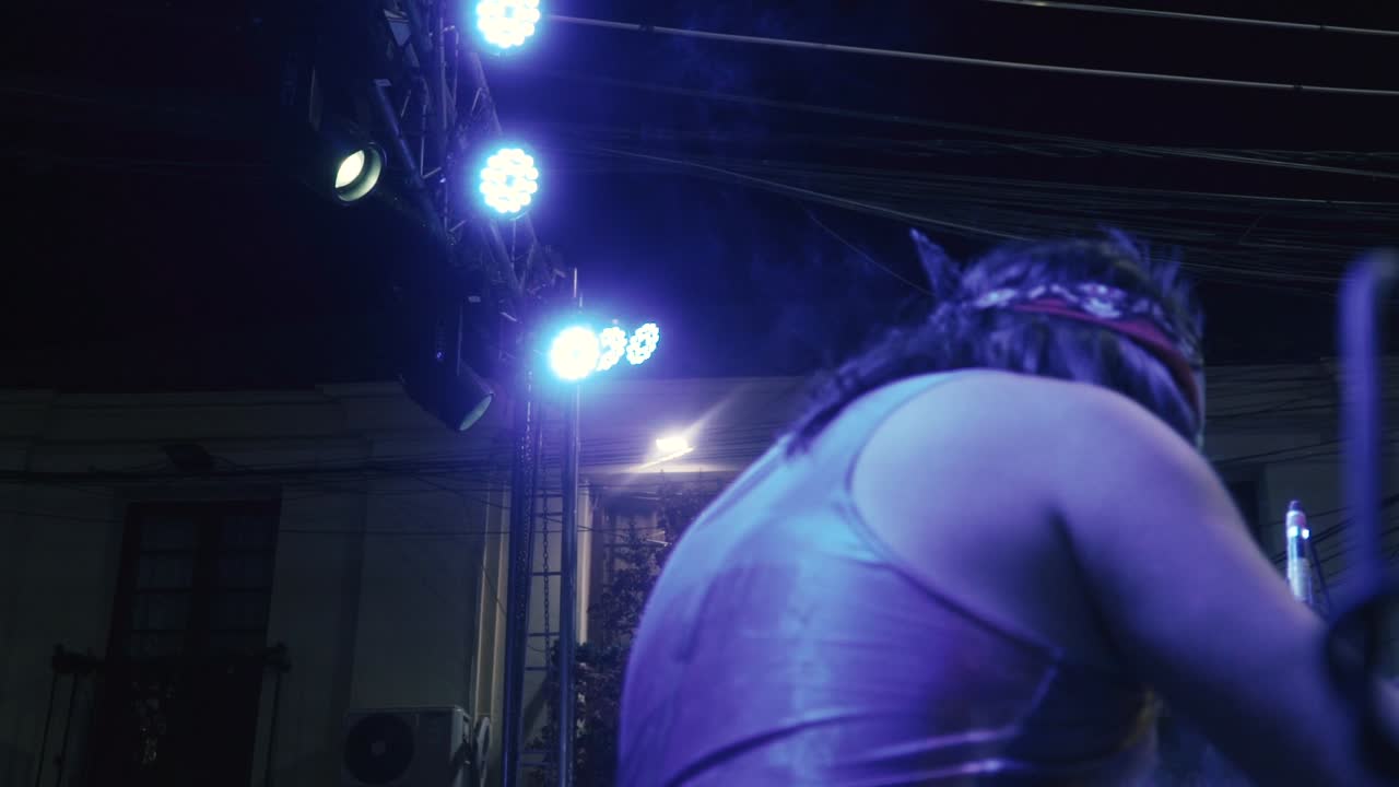 Camera moving from left to right side on the right side of a drummer playing a song in an outdoor concert