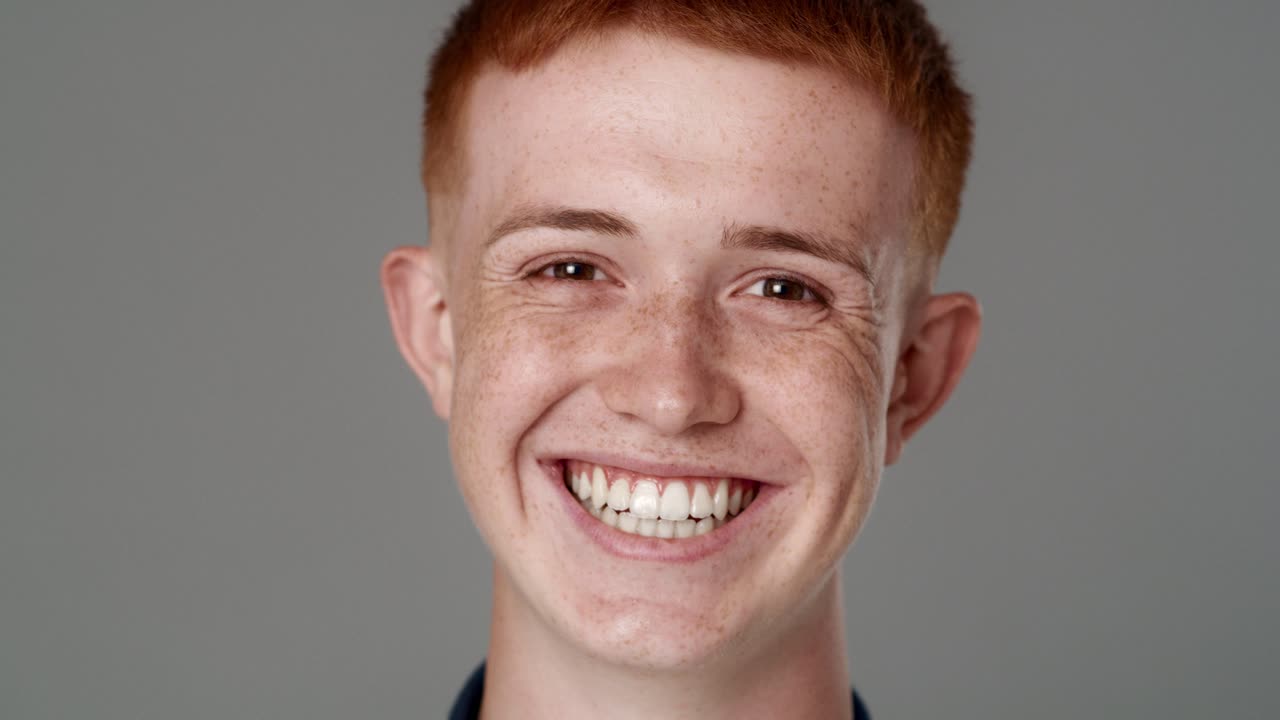Retrato em close-up de um jovem caucasiano ruivo com um sorriso largo.
