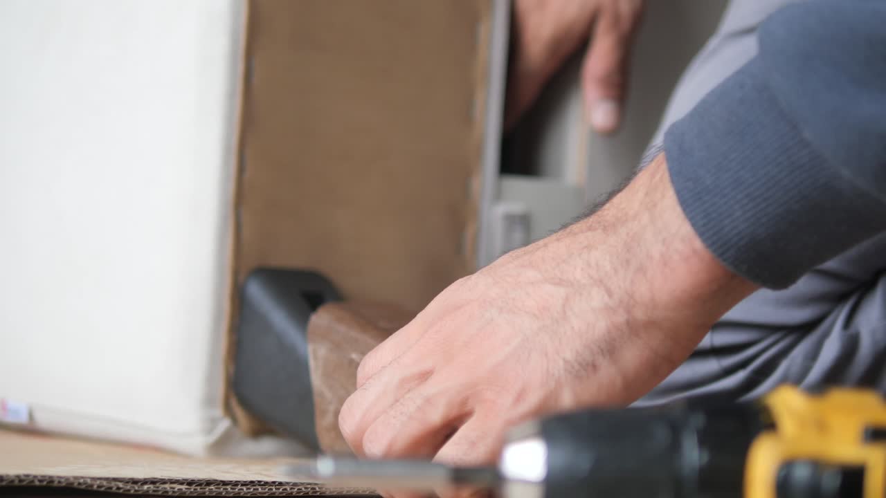 A man assembles furniture with a drill