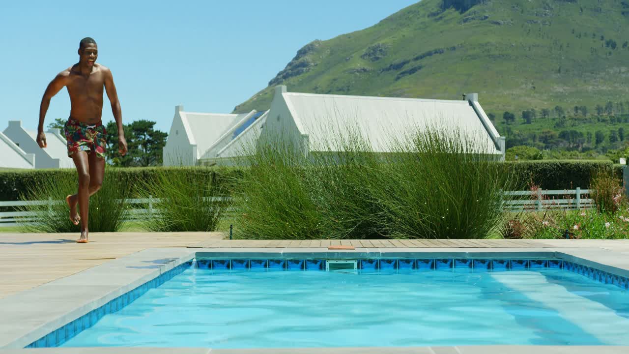 joven negro saltando en la piscina en el resort 4k