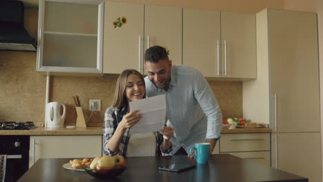 couple reading a letter together in kitchen
